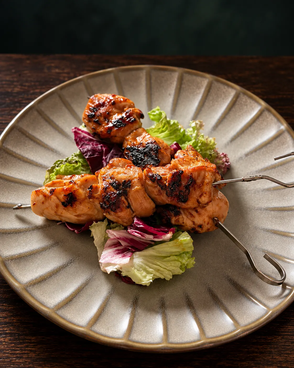 Glazed chicken skewers with char marks over lettuce and radicchio